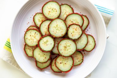 Round cucumber slices sprinkled with Tajin seasoning arranged in a bowl