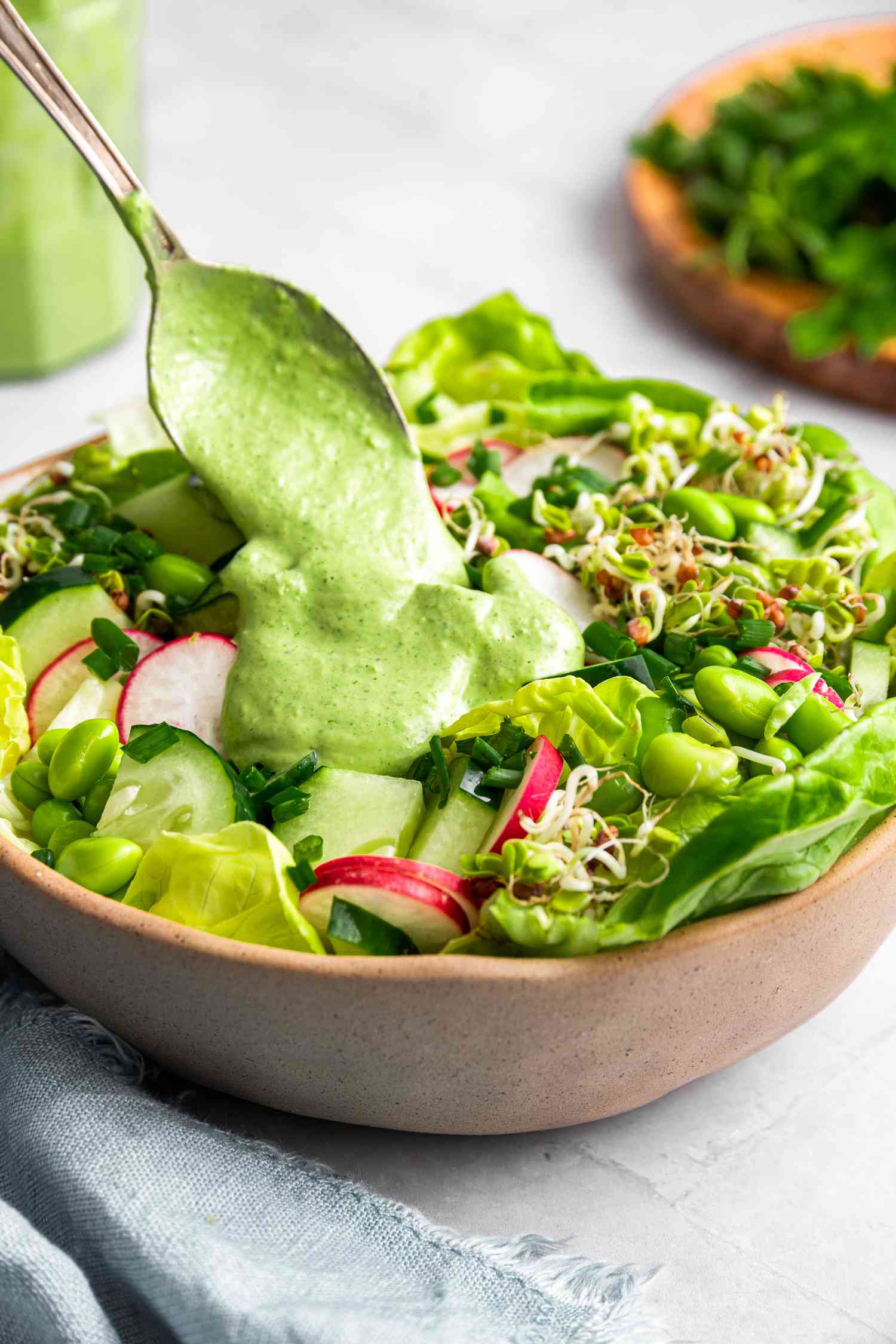 Homemade Green Goddess Dressing Spooned into a Bowl of Salad