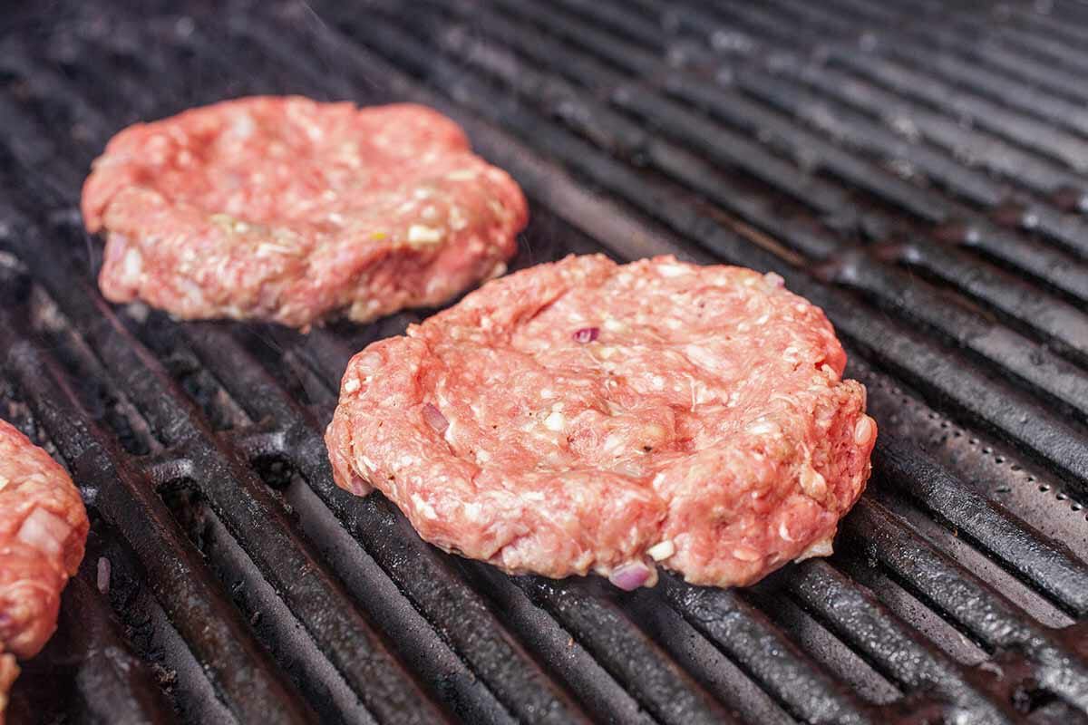 Raw burger patties cooking on a grill