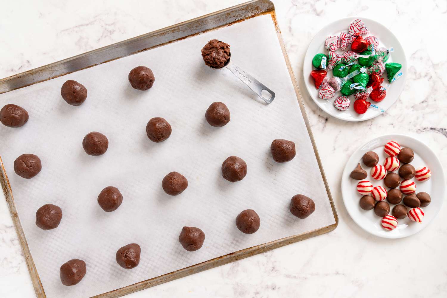 Tray with chocolate dough scoops and plates of candy for making bonbons