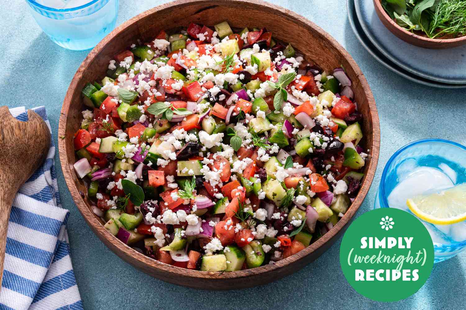 A colorful Greek salad in a wooden bowl on a blue table