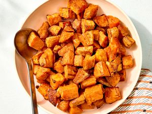 Overhead view of a bowl with cubes of roasted sweet potato along with a metal spoon