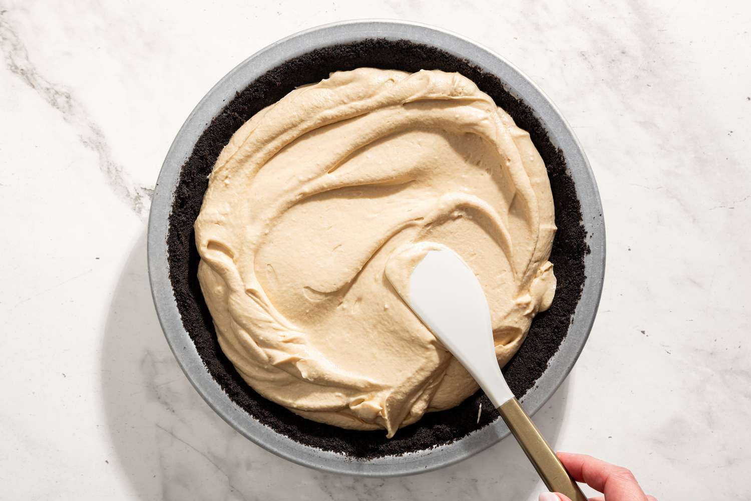 hand spreading pie filling into pie shell for No-Bake Fluffernutter Pie