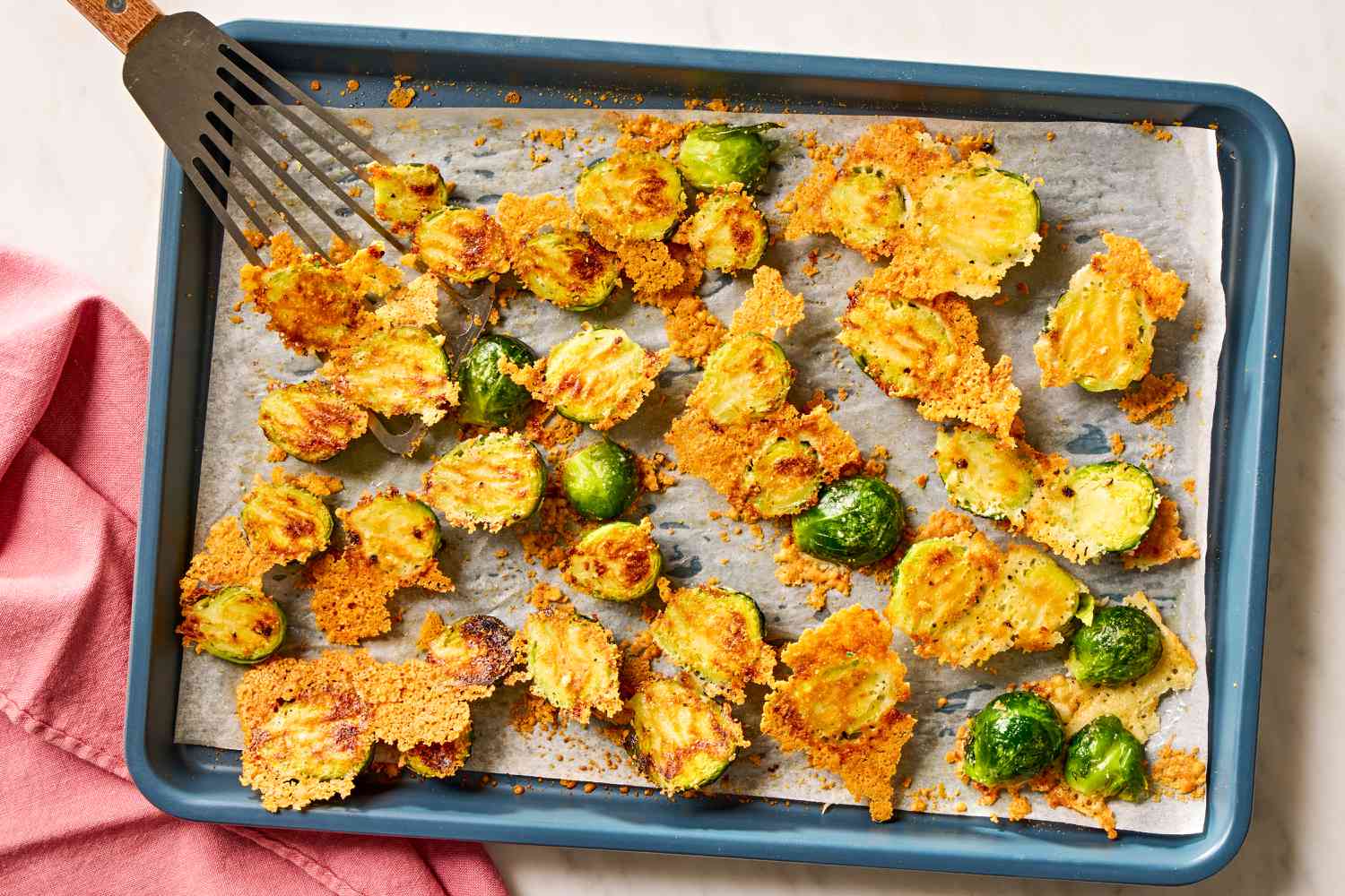 Overhead view of a baking sheet of roasted brussels sprouts and parmesan on parchment paper