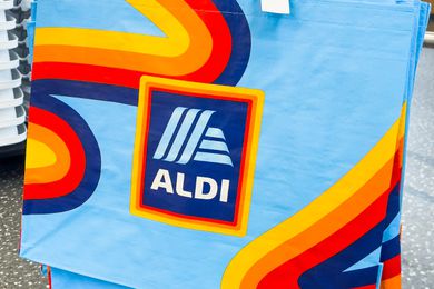Reusable bag featuring the Aldi logo and colorful design, stacked display in background