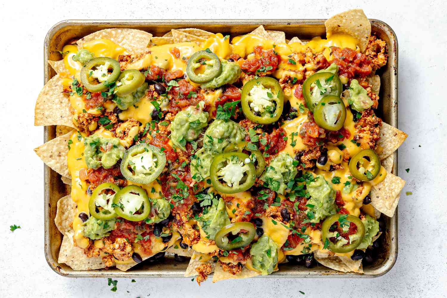 Vegan Nachos Tipped with Guacamole, Salsa, and Pickled Jalapenos