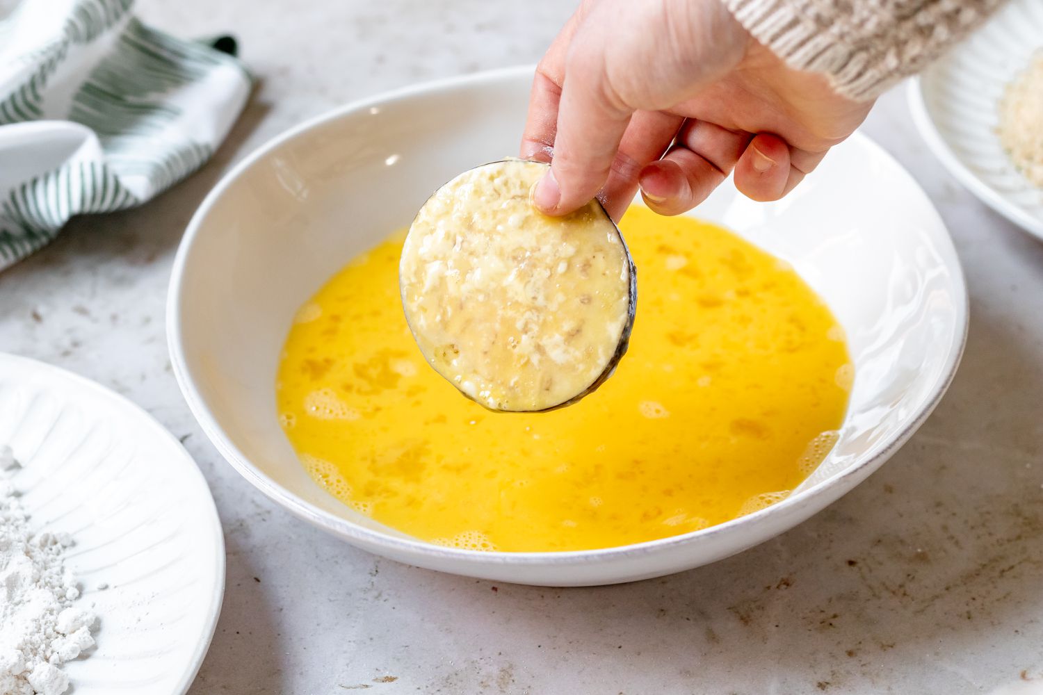 Dipping a floured eggplant slice in an egg wash
