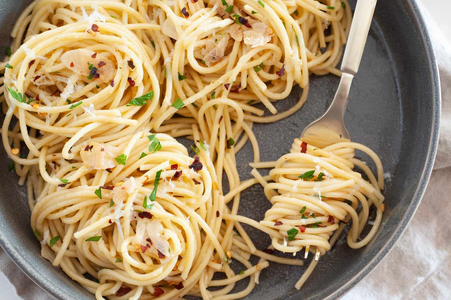 Spaghetti Aglio e Olio (Pasta With Garlic and Oil) on a Fork and in a Bowl