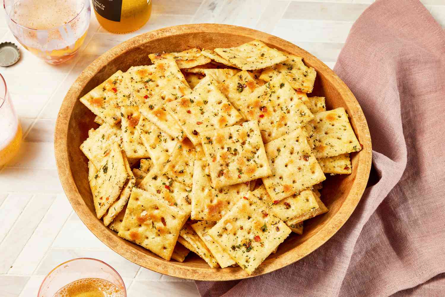 Bowl of Alabama fire crackers surrounded by a bottle and glasses of beer and a light maroon table napkin