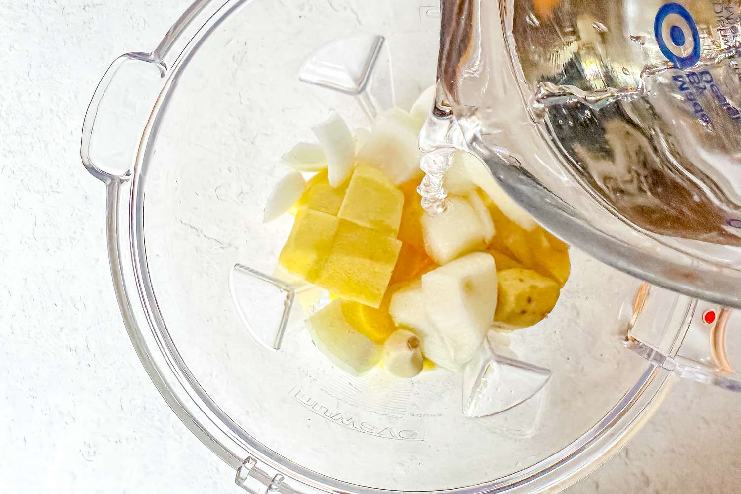 Water from a Glass Measuring Cup Poured Into a Blender With Garlic, Ginger, Asian Pears, and Onions for Naengmyeon Recipe