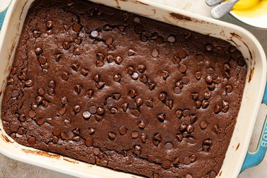 Overhead view of a baking dish of baked batter for Chocolate Dump Cake recipe on a tan countertop