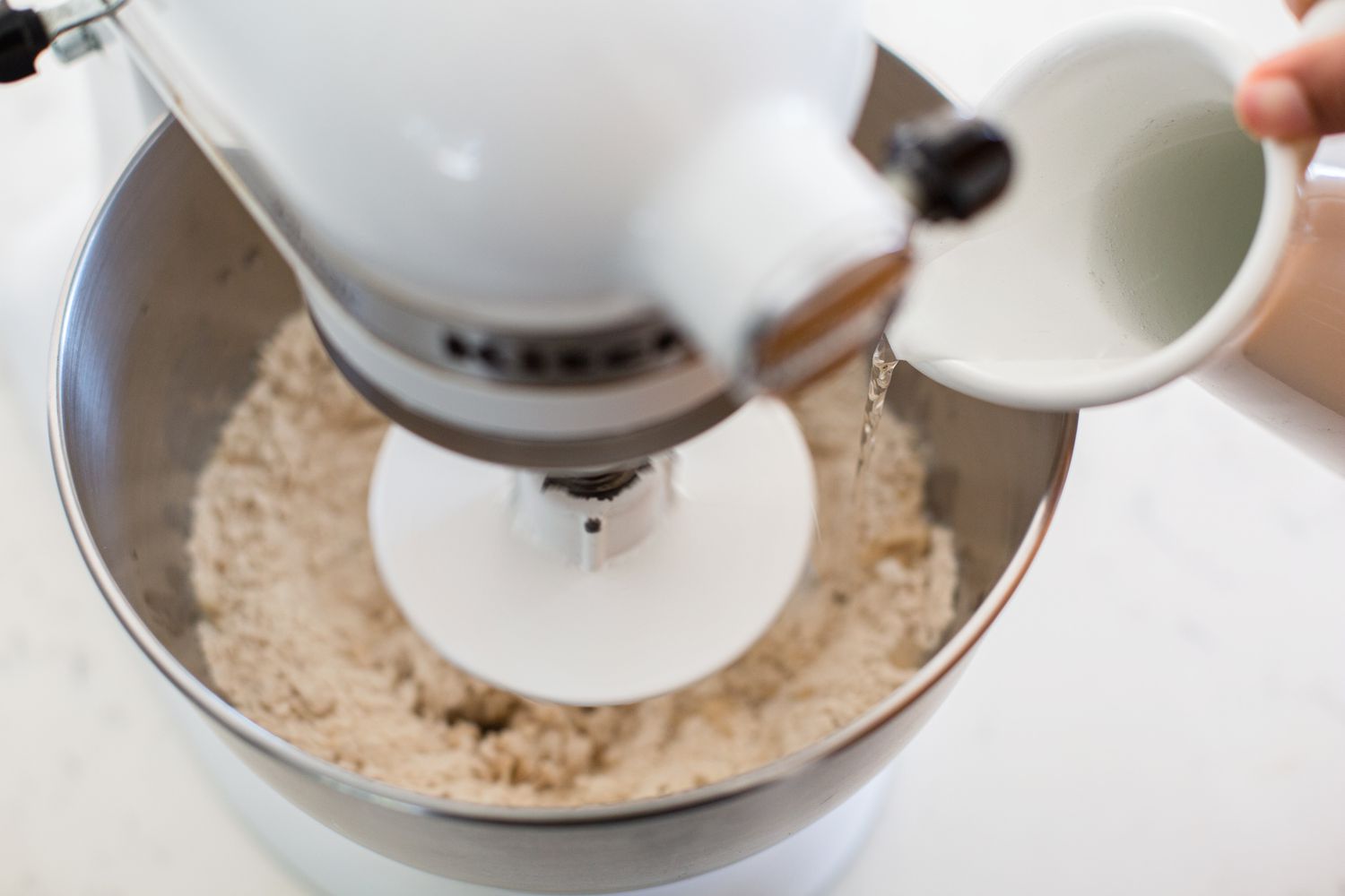Kneading dough in a stand mixer to show how to make roti.