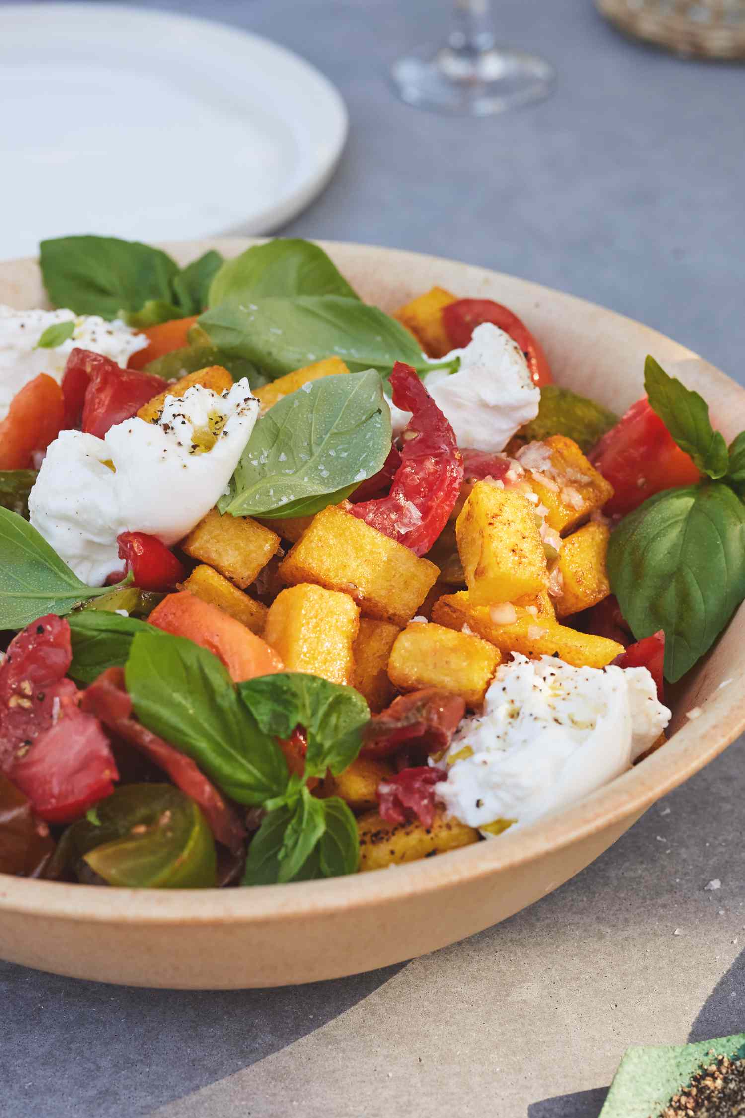 Bowl of Fried Polenta Panzanella with Tomato, Basil, and Burrata on a Table
