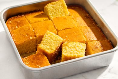 A square pan containing cut pieces of cornbread some pieces slightly raised