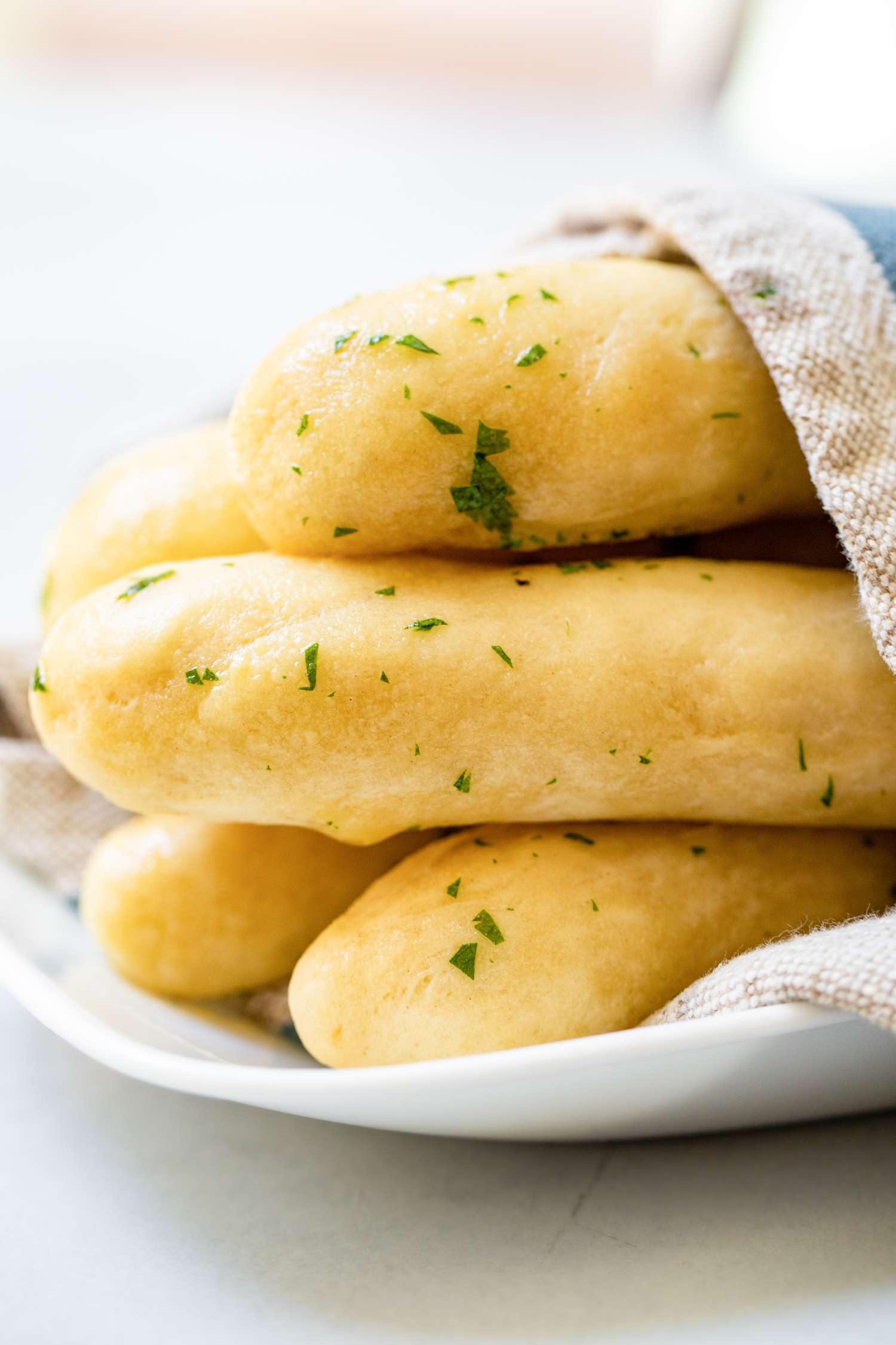 Breadsticks with Garlic Butter on a Plate Covered with a Kitchen Towel