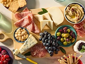 Charcuterie board with cheese meats grapes and accompaniments