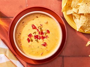 Ro-Tel dip in a bowl at a table setting with a bowl of chips and a glass of beer