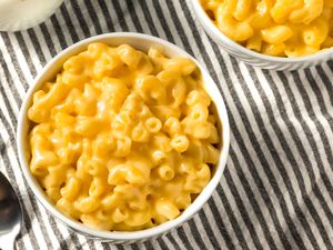 A bowl of macaroni and cheese on a striped cloth