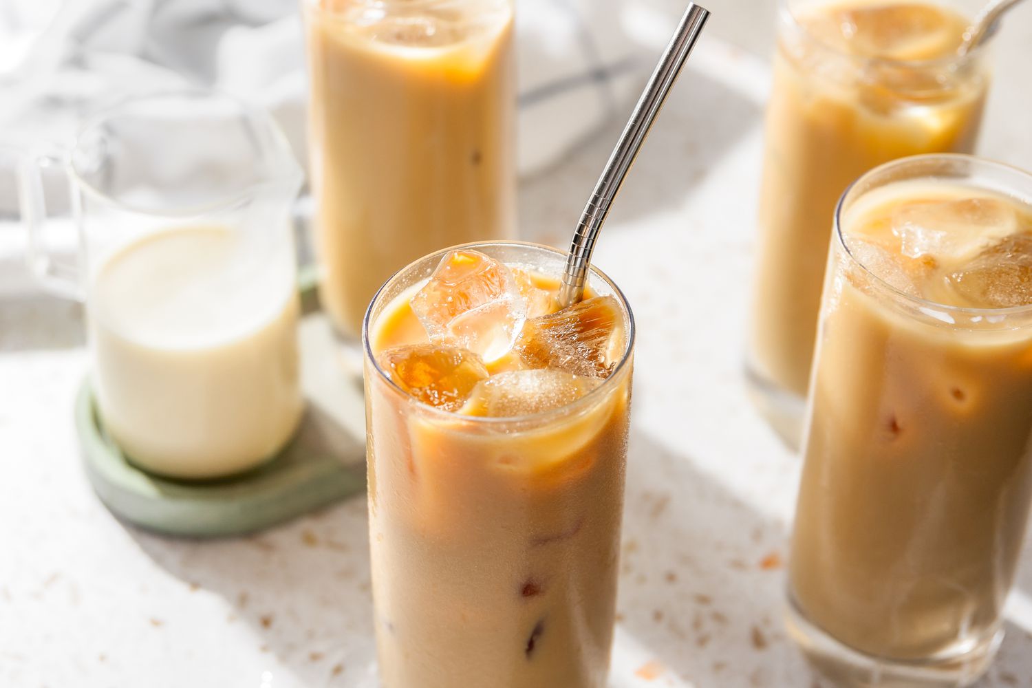 Overhead Shot of a Glass of Thai Iced Tea With a Straw, and in the Surroundings, More Glasses of Thai Iced Tea and a Glass Creamer With Milk