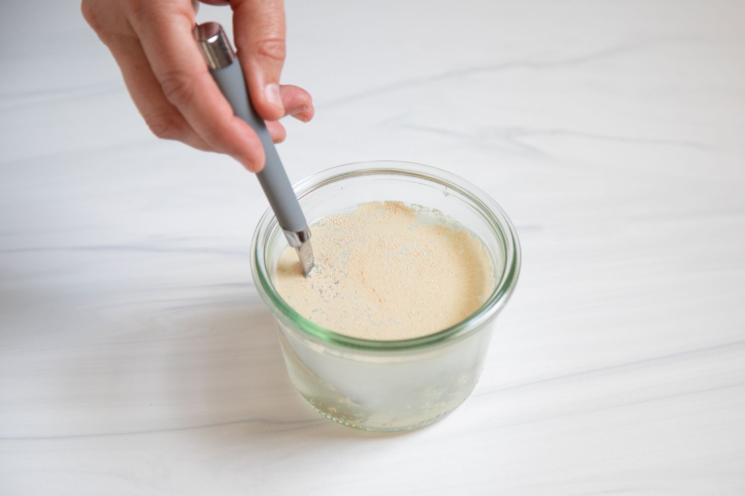 Stirring yeast and water in a glass cup.