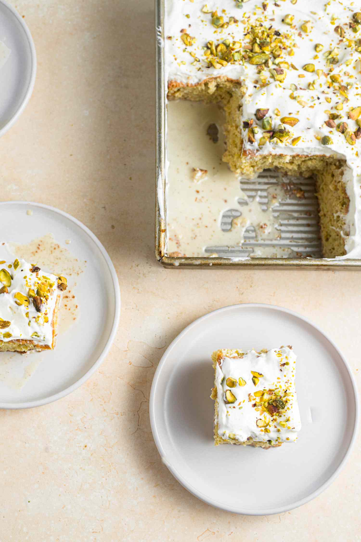 Plates of Tres Leches with Pistachio and Cardamom with the Rest in a Baking Tray