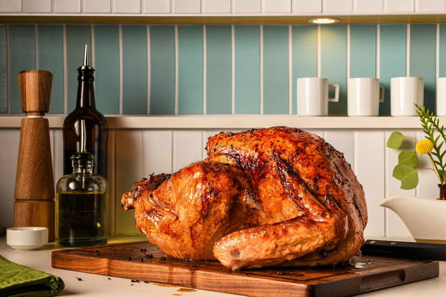 Roasted turkey on a wooden cutting board with kitchen items in the background