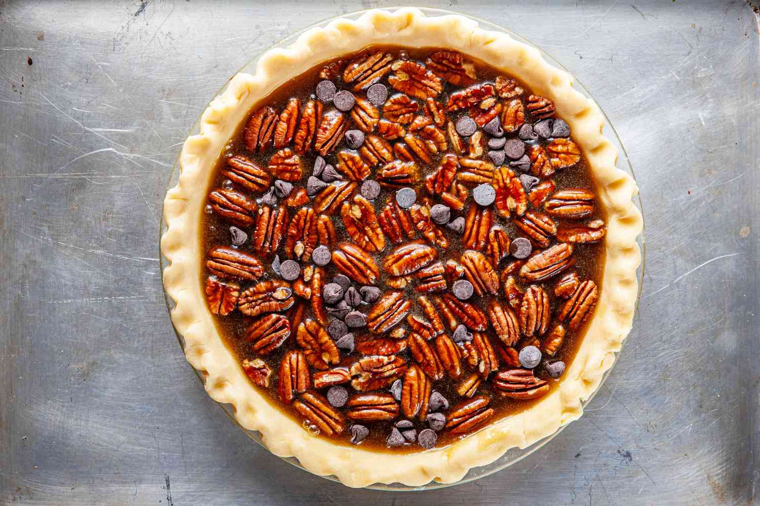 Bourbon-flavored chocolate pecan pie on a baking sheet and ready to be baked.