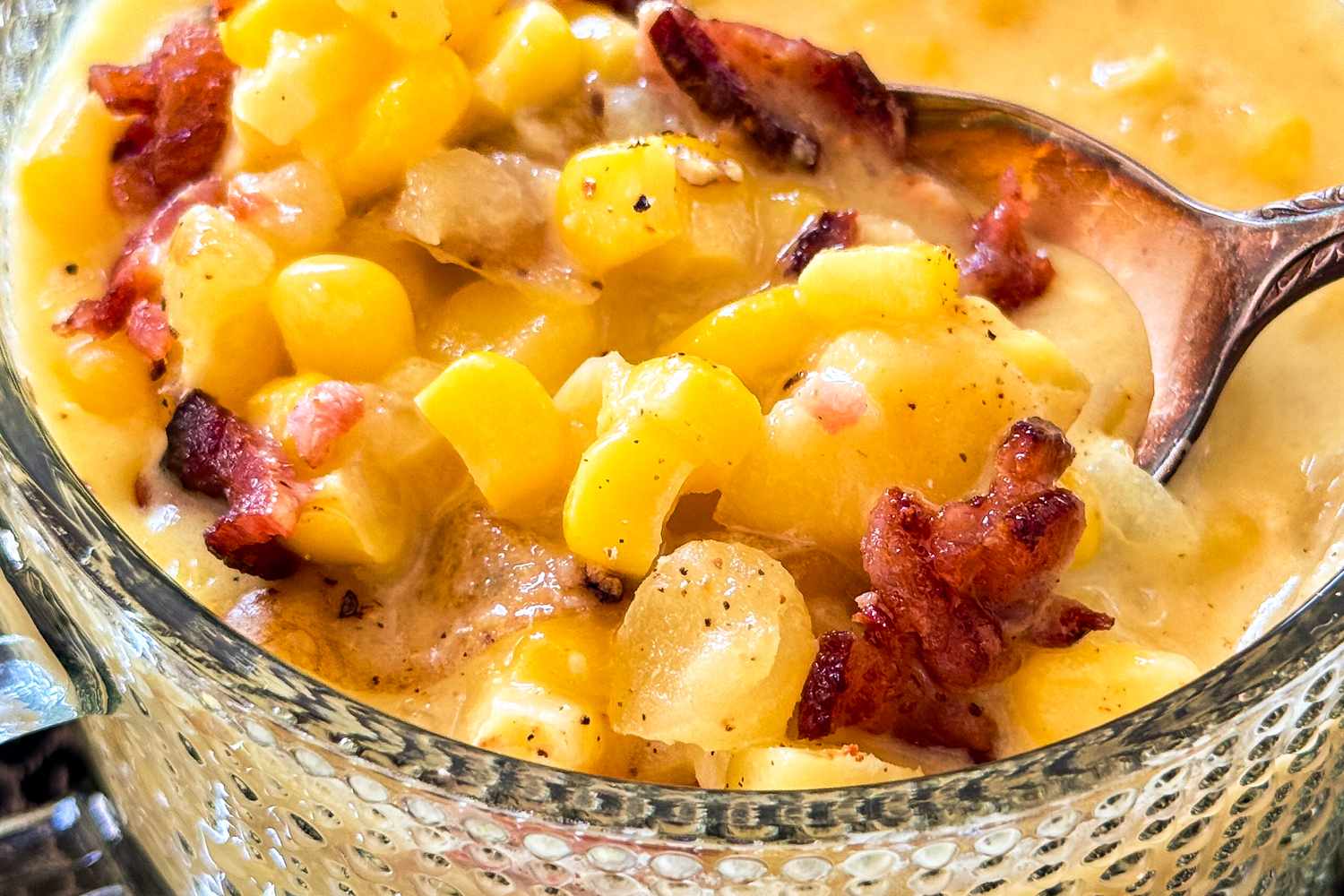 Bowl of corn chowder with bacon and a spoon