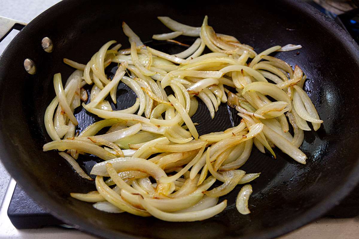 Onions cooked in a skillet for a broccoli rabe recipe.