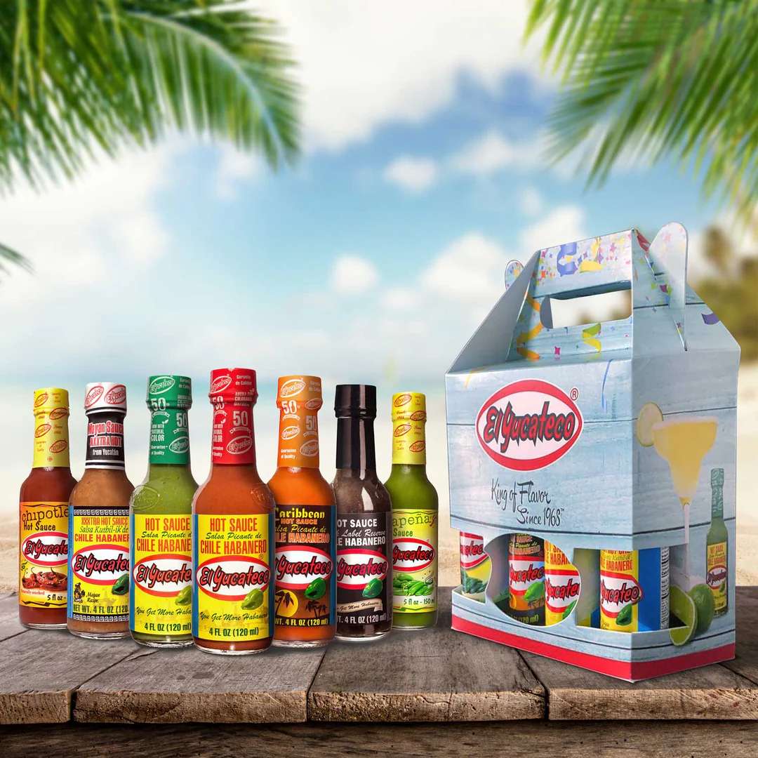 A variety pack of hot sauces displayed on a wooden table outdoors with a scenic tropical background
