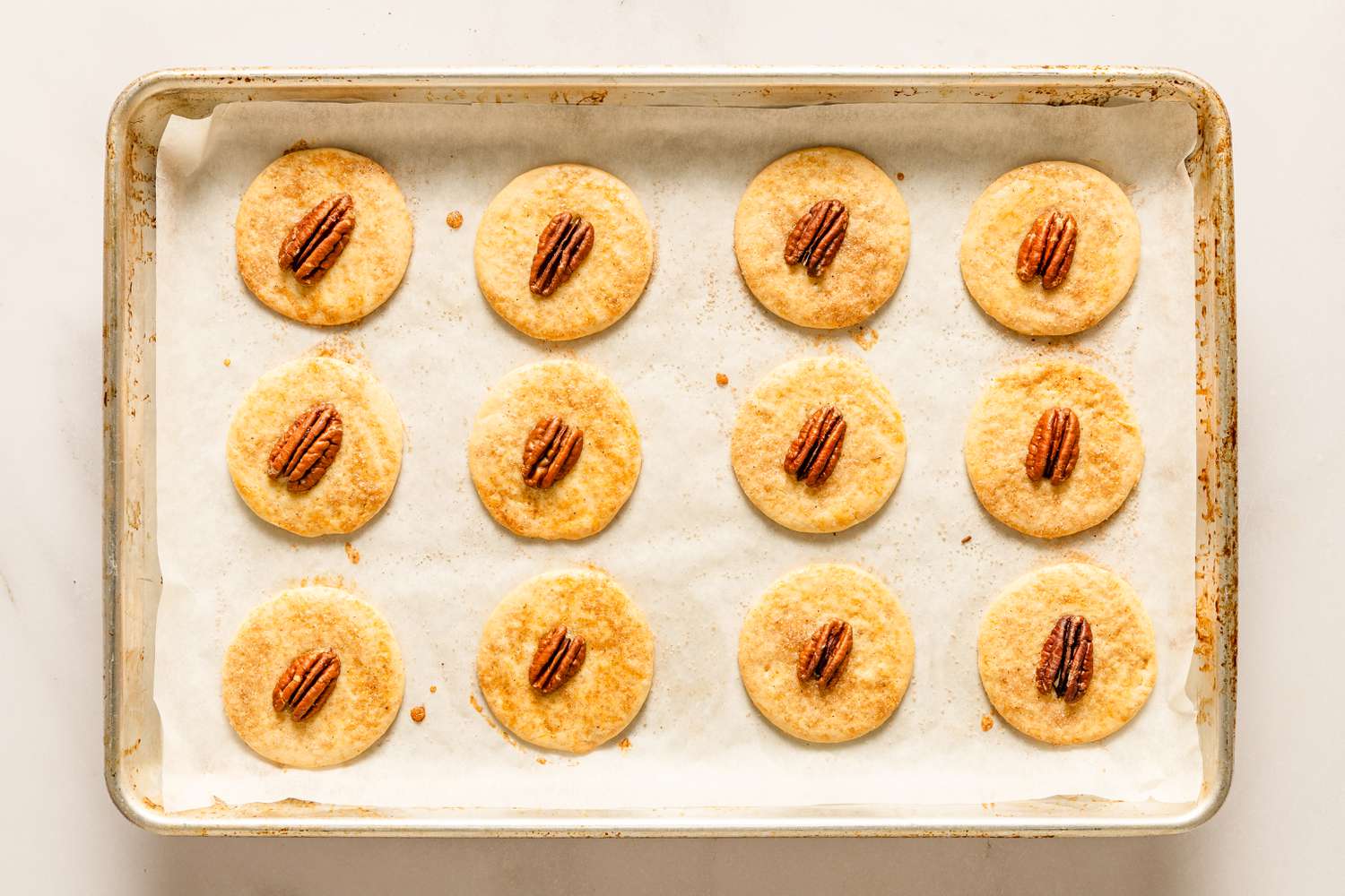 Overhead view of twelve cookies on a baking sheet after baking for Sand Tarts recipe