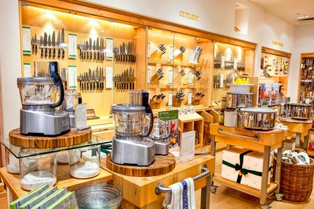 A display of kitchenware and cooking tools in a store featuring a variety of knives food processors and utensils