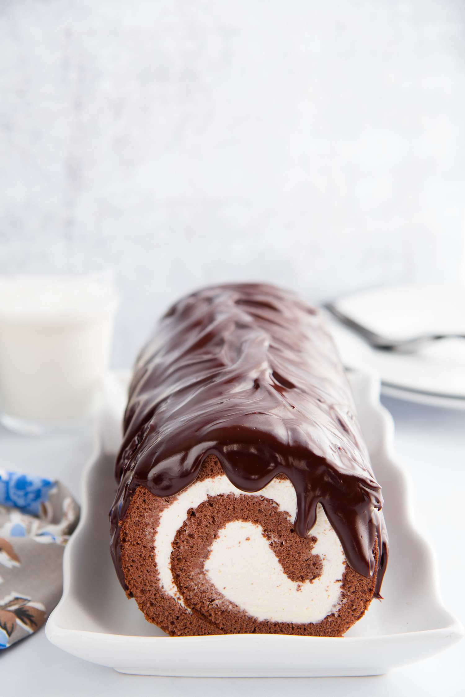 Side view of a chocolate swiss roll topped with chocolate ganache.