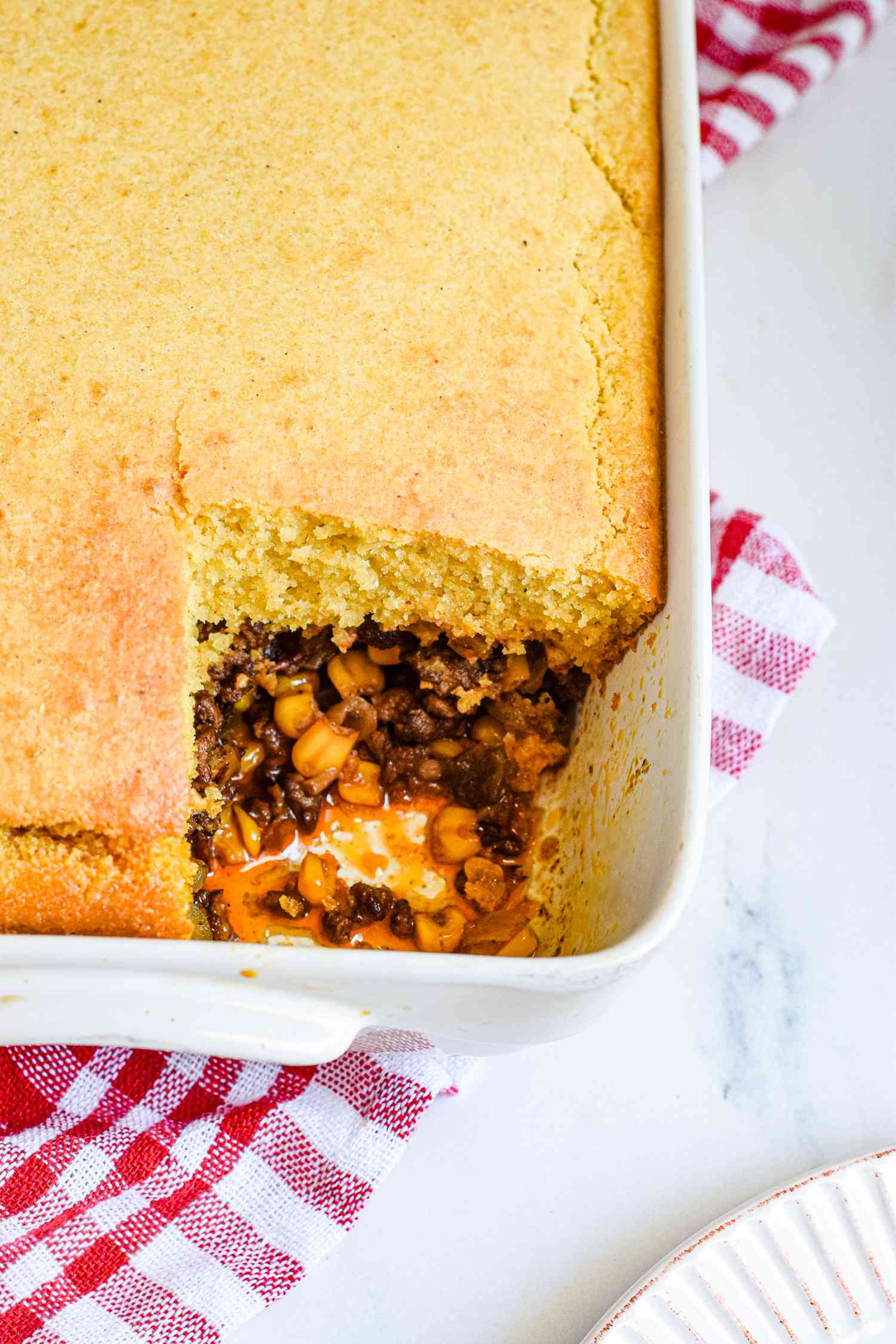 A casserole dish with a tamale pie and a piece missing.