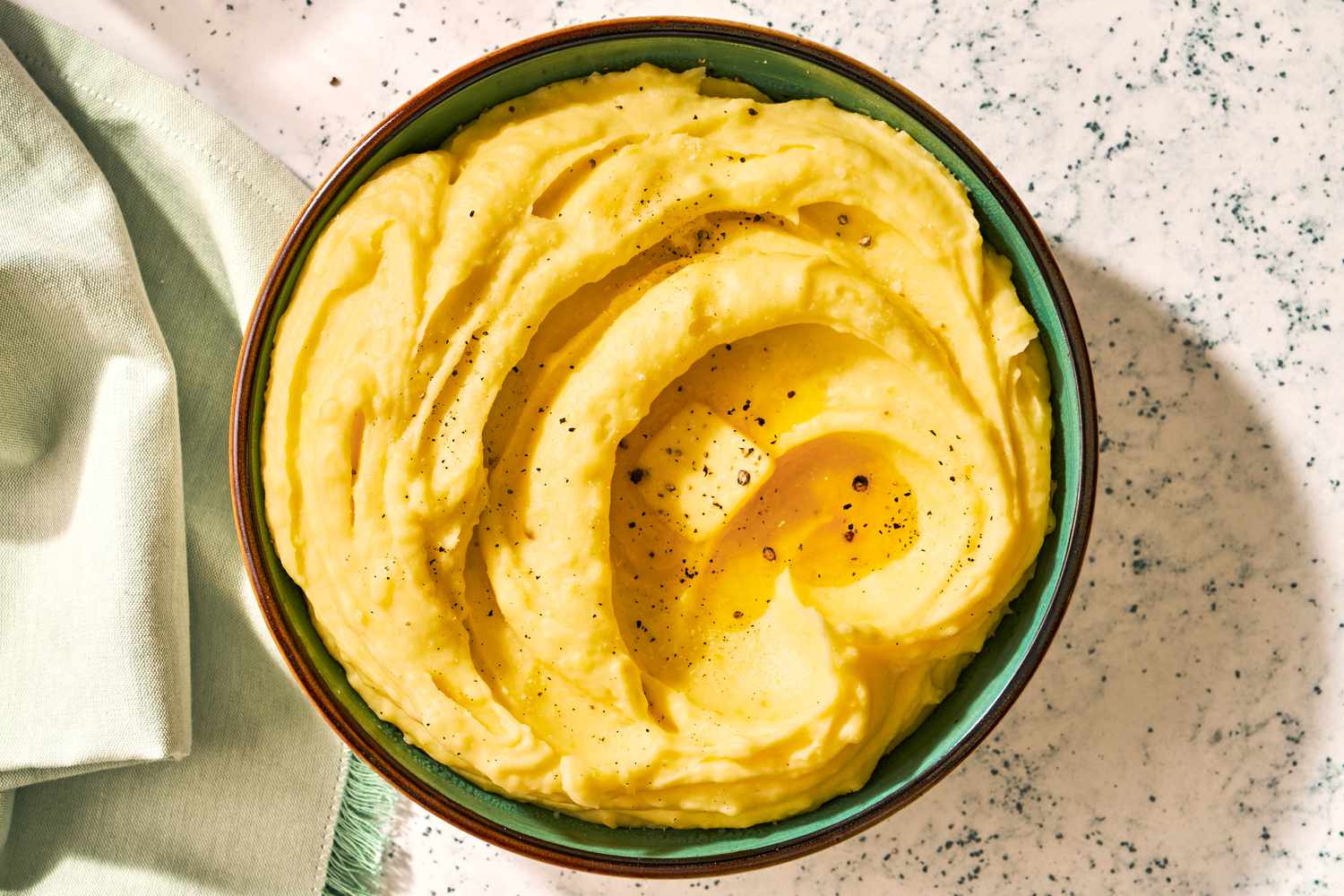 Golden mashed potatoes with a melting pat of butter and black pepper on top