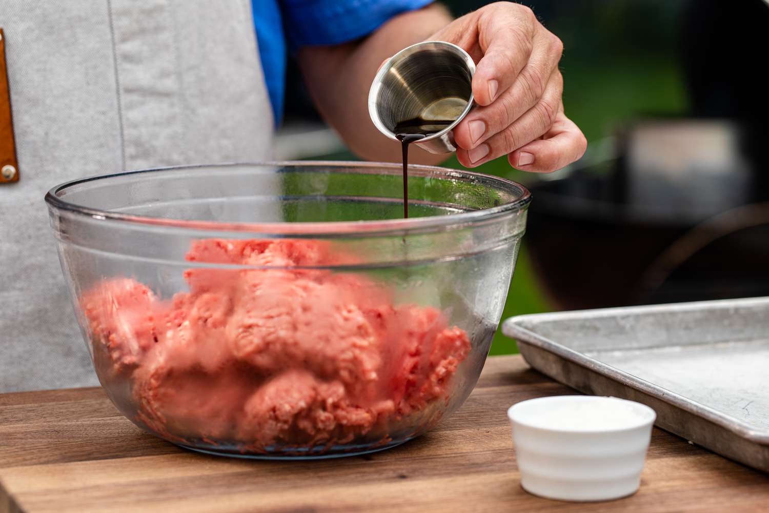 Worcestershire sauce being added to a bowl of ground beef.