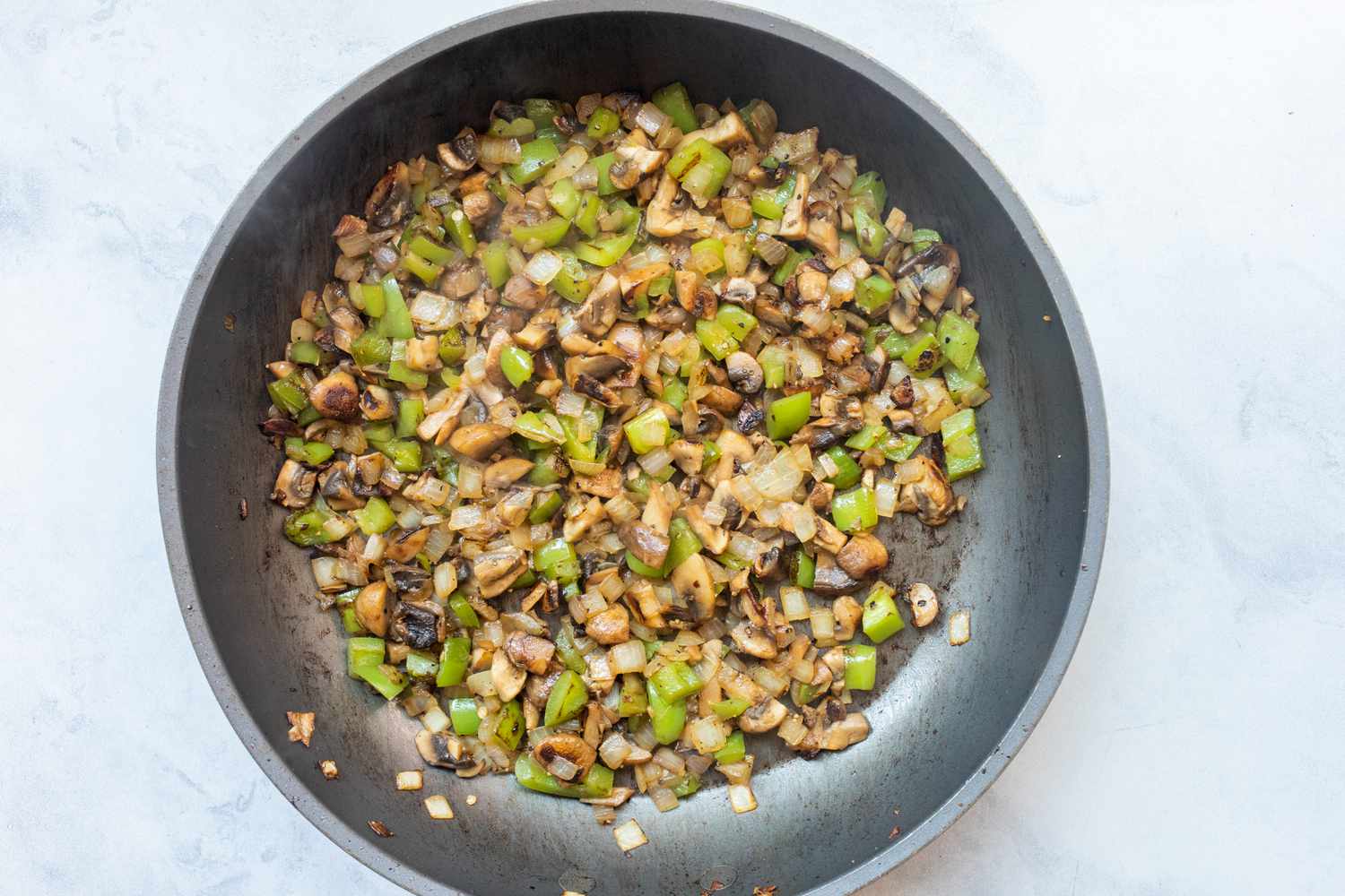 Bell peppers and onions cooked in skillet.