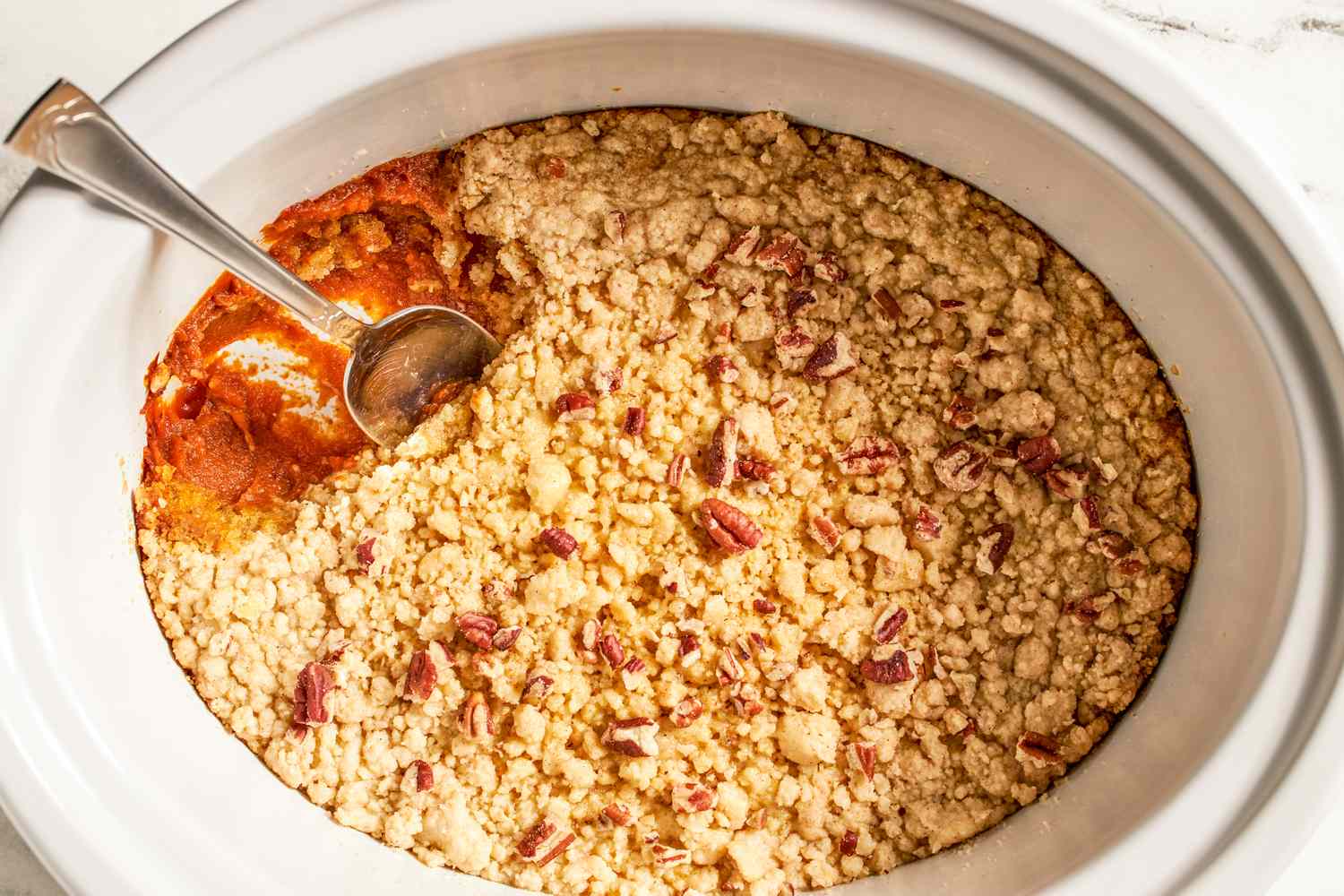 Slow cooker pumpkin dump cake with a serving spoon scooping a portion