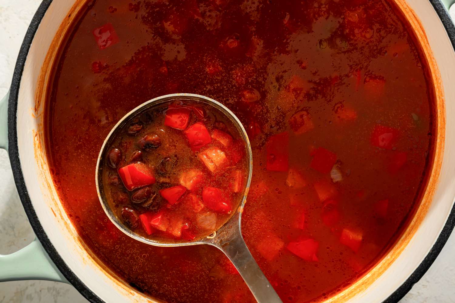 Soup with vegetables and beans in a ladle inside a large pot
