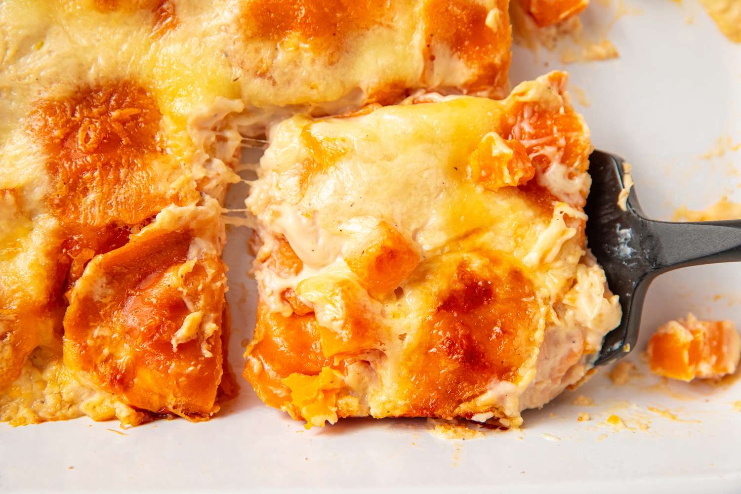 A serving of butternut squash ravioli lasagna being served with a spatula