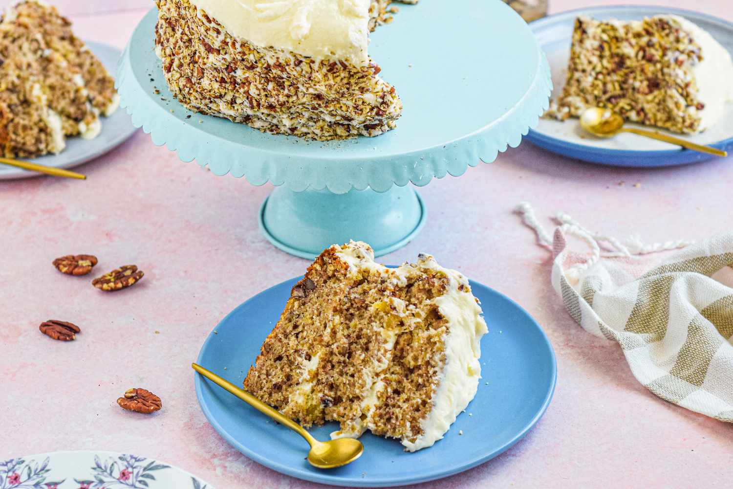 Cake stand with hummingbird cake and blue plates with slices set around it.