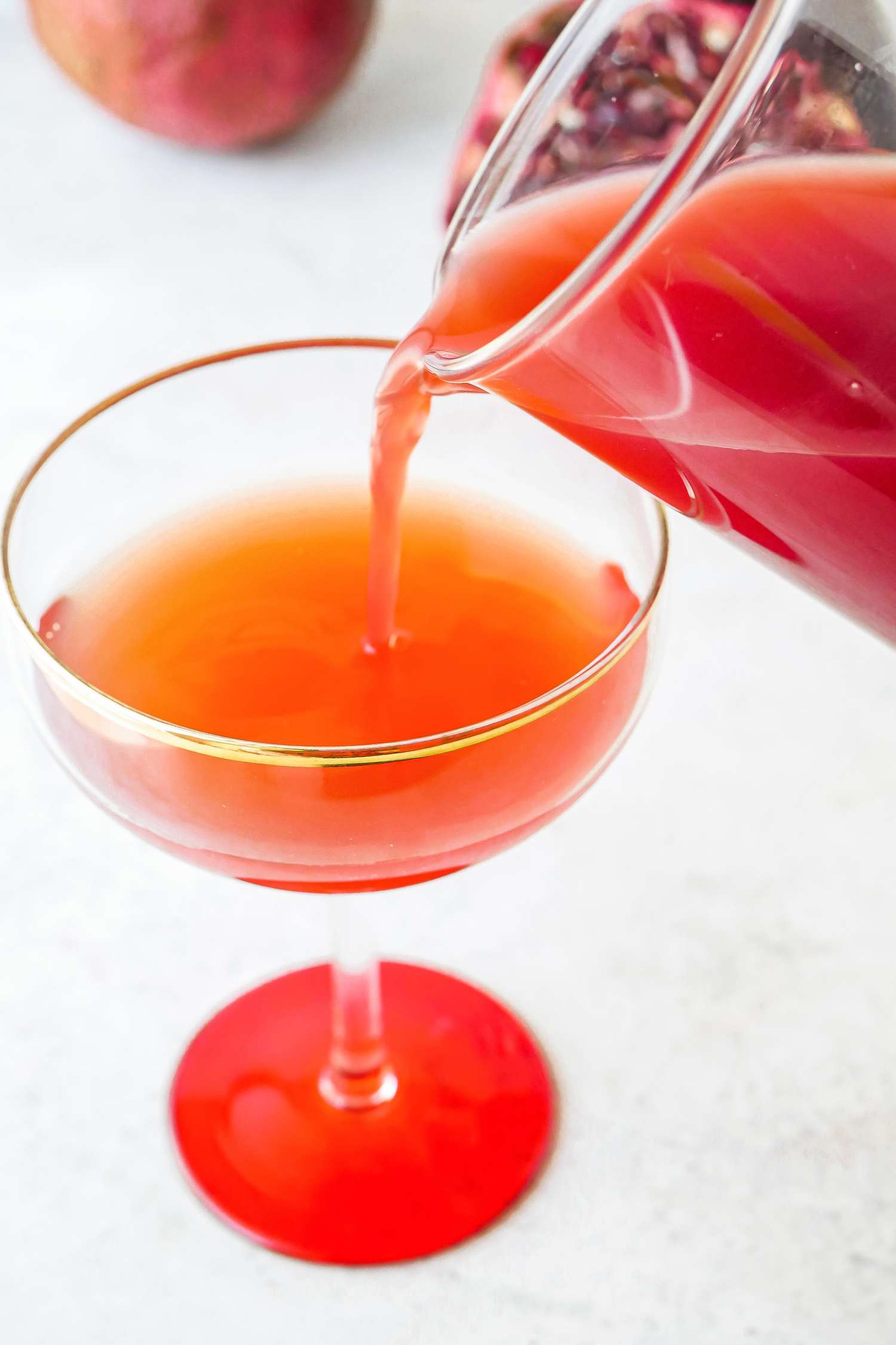 Pouring Grenadine Cocktail Syrup into a coupe glass.