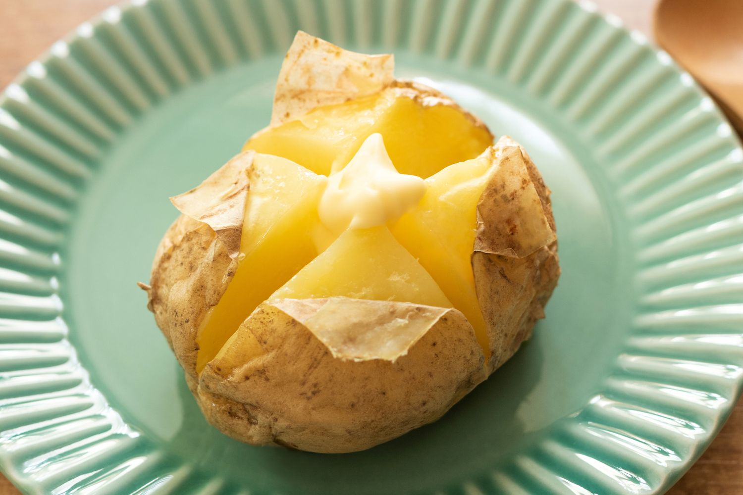 Baked potato served on a plate topped with a dollop of butter
