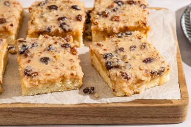 Slices of Lane cake with a fruit and nut topping on a wooden board