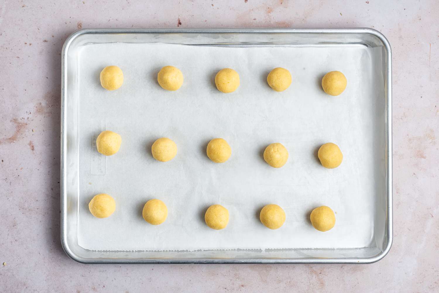 Balls of dough on a parchment paper-lined baking sheet