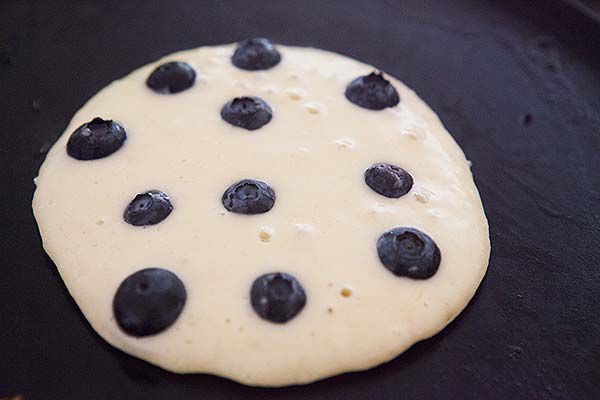 Blueberry pancakes cooking on skillet