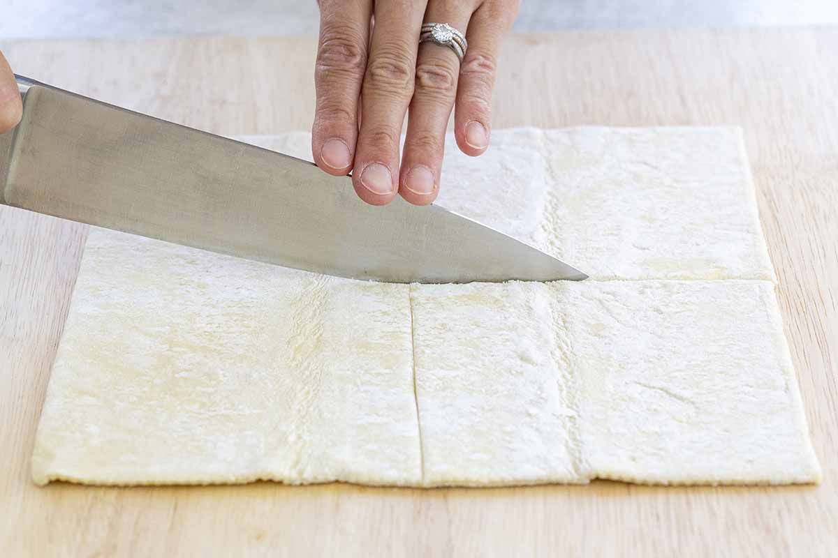 Puff pastry sheets being cut to top vegetarian pot pies.