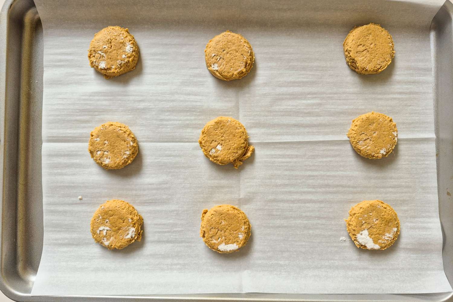 Nine unbaked cookie dough rounds arranged on a parchmentlined baking sheet