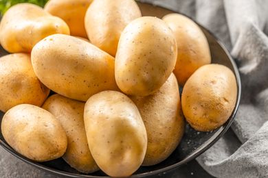 Raw potatoes on a black plate on the kitchen table