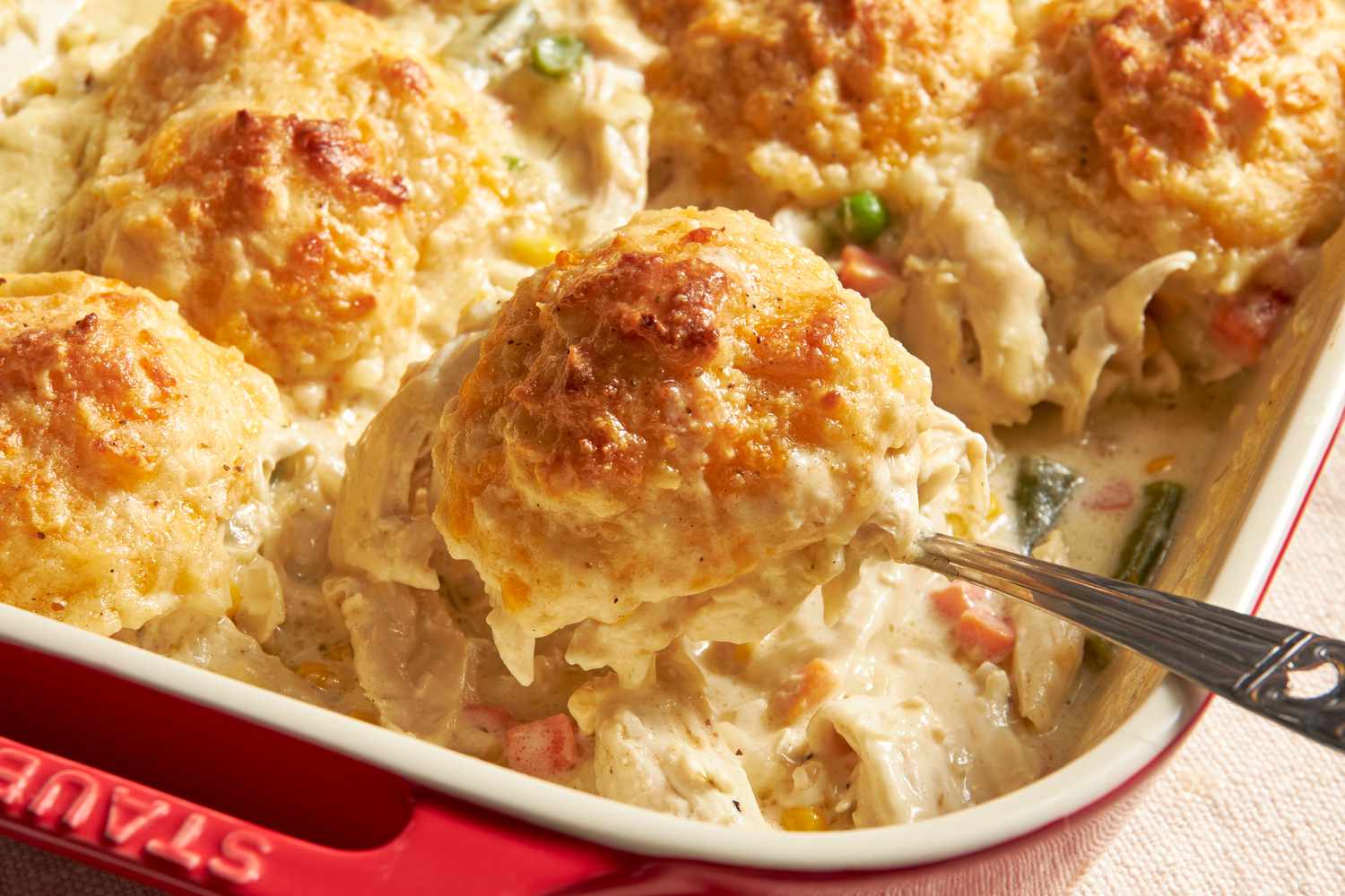 Close-up: Chicken Cobbler Recipe With Cheddar Bay Biscuit Top in a casserole dish (a biscuit lifted using a spoon)